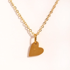 Vue macro détaillée d'un collier pendentif coeur doré gravé avec la lettre T personnalisée
