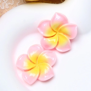 Close-up of pink and yellow gradient resin plumeria flowers for DIY crafts decoration