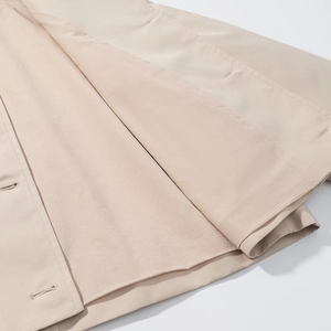 Close-up of beige twill trench coat showing premium lining and detailed stitching