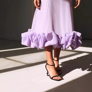 Elegant purple A-line evening dress with dramatic ruffled hem and stylish stiletto heels