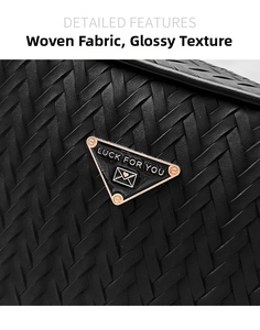 Detailed macro view of black woven faux leather bag texture and triangular metal plaque
