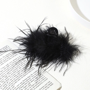 Detail shot of fluffy black ostrich feather hair claw clip on an open book background
