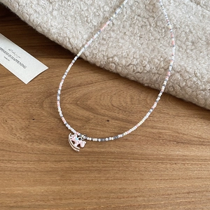 Détail du collier de perles avec pendentif cheval à bascule rose sur tissu polaire