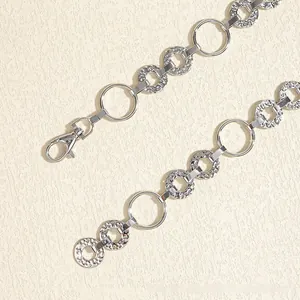 Close-up of a silver metal chain belt with polished rings and hammer texture details