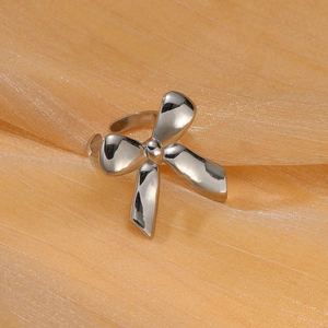Silver bow-shaped stainless steel open ring displayed on soft orange silk fabric