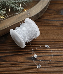 Macro view of clear star bead chain on wood background with festive Christmas light