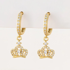 Close-up of golden crown earrings with micro-paved cubic zirconia on white display