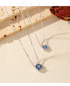 Detailed close-up of S925 silver necklace with blue gemstone on decorative stone