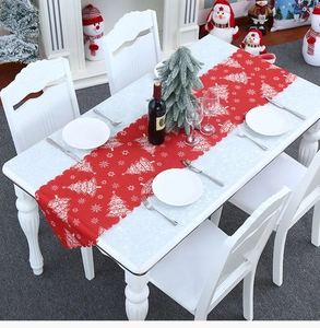 Festive red Christmas table runner with white tree prints on a decorated dining table