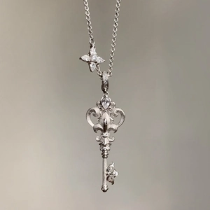 Close-up detail view of a silver stainless steel key pendant necklace with sparkling zircons