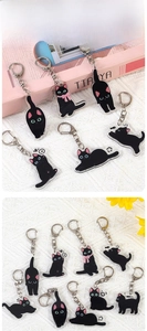 Detailed view of black cat acrylic keychains with silver lobster clasps on woven fabric