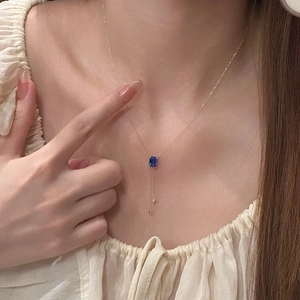 Collier élégant en or avec pendentif saphir bleu taille émeraude et pompons métalliques