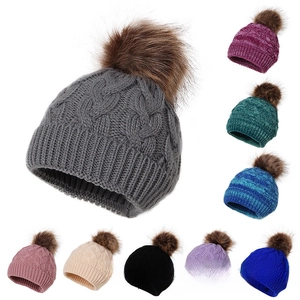 Detail of winter knit hats with fluffy faux fur pom-poms in nine vibrant color options