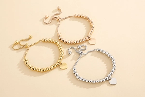 Detailed view of adjustable beaded bracelets with heart pendants in gold, silver, and rose gold