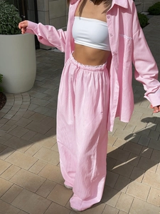 Detail of pink and white striped shirt and wide-leg trousers set with fabric texture