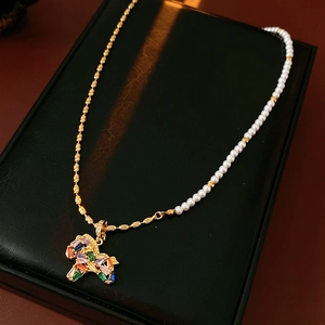 Close-up of vintage zircon pony necklace with gold chain and white pearl details