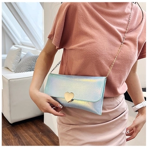 Holographic light blue heart purse with gold chain strap worn by a model in lifestyle setting