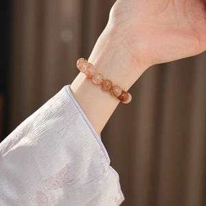 Close-up of natural red quartz beaded bracelet with sparkling inclusions on a model's wrist