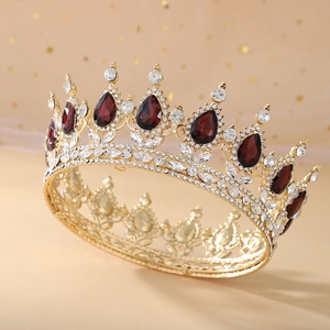 Detailed close-up of golden Baroque crown with clear crystals and red teardrop gems
