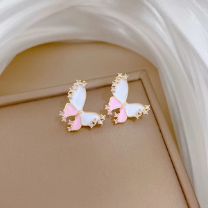 Close-up of gold butterfly earrings with pink enamel and sparkling zircon details
