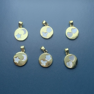 Close-up of gold shell pendants with heart star and moon motifs on blue leather
