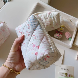 Gros plan détaillé d'une trousse à maquillage matelassée avec motif floral et fermeture
