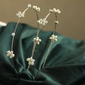 Dettaglio di cerchietti dorati con perle finte e strass su velluto verde scuro