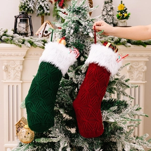 Close-up of knit Christmas stockings with faux fur trim hanging on a decorated tree