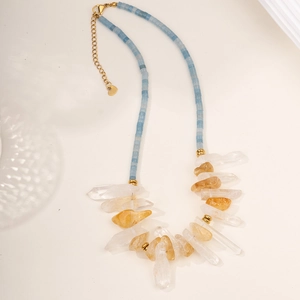 Detailed view of light blue beads, natural crystal pillars and gold fish pendant on necklace