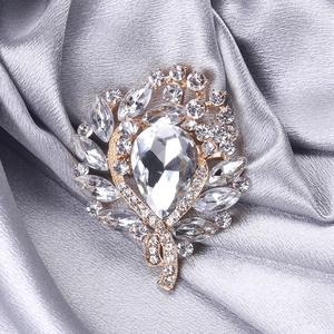 Detail of crystal brooch with pear-shaped main stone on elegant silver silk fabric