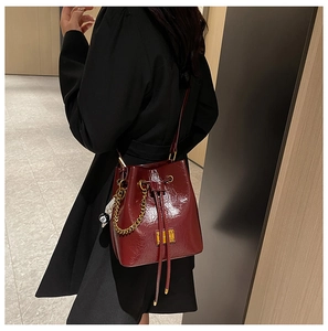 Détail du sac seau bordeaux en cuir verni avec chaîne dorée et breloque de billard