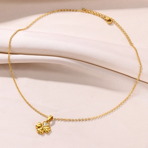 Detail shot of the 18K gold clover pendant with sparkling zircon accents on white fabric