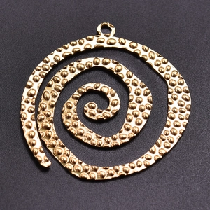 Macro shot of 304 stainless steel golden spiral pendant with textured surface detail