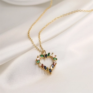 Collier cœur doré avec pierres en zircon colorées sur fond de soie blanche