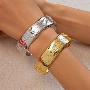Detail of gold and silver open bangles with intricate vintage scroll pattern embossing