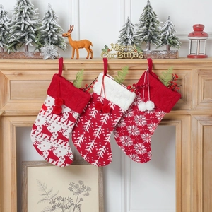 Knitted Christmas stockings with reindeer and snowflake patterns on a rustic wooden mantel