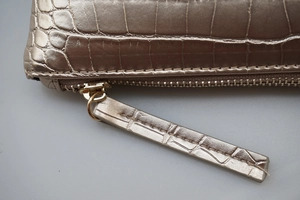 Macro shot of champagne gold crocodile pattern leather clutch with zipper detail
