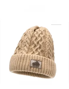 Dettaglio del berretto in maglia a trecce kaki con toppa in pelle e motivo montano