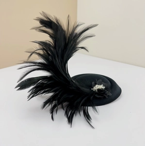 Close-up of black fascinator hat with feathers, fabric flower and pearl accents