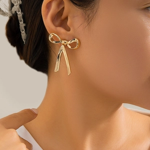 Elegant gold bow-knot earrings with a polished metallic finish on a model's ear