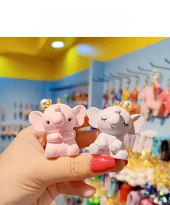 Close-up of cute resin elephant figurines with golden crowns in pink and purple colors
