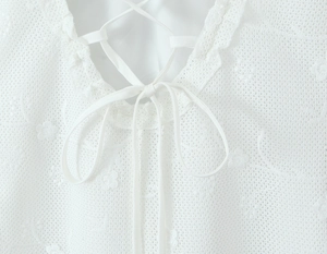 Close-up of white mesh lace neckline with intricate floral patterns and lace-up details
