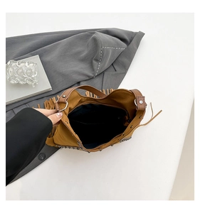 Detail of brown suede tassel bag featuring metallic rivets and black interior lining