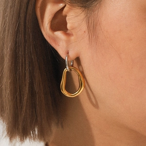 Minimalist bicolor stainless steel geometric earrings worn by model in warm light