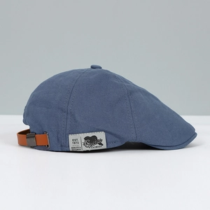Detail of navy blue fabric cap with brown leather strap and vintage brand label