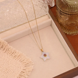 Star-shaped natural stone pendant on a delicate gold chain over a wooden jewelry tray