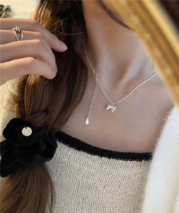 Detail shot of a minimalist s925 sterling silver bow necklace with extension chain on model