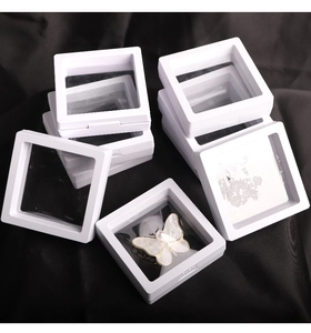 Macro detail of white PE film floating jewelry cases stacked on black silk background