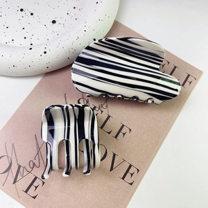Minimalist black and white zebra striped hair claw clip set on a decorative beige card