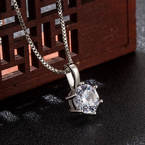 Close-up of 2 carat round zircon pendant with silver four-prong setting and fine chain